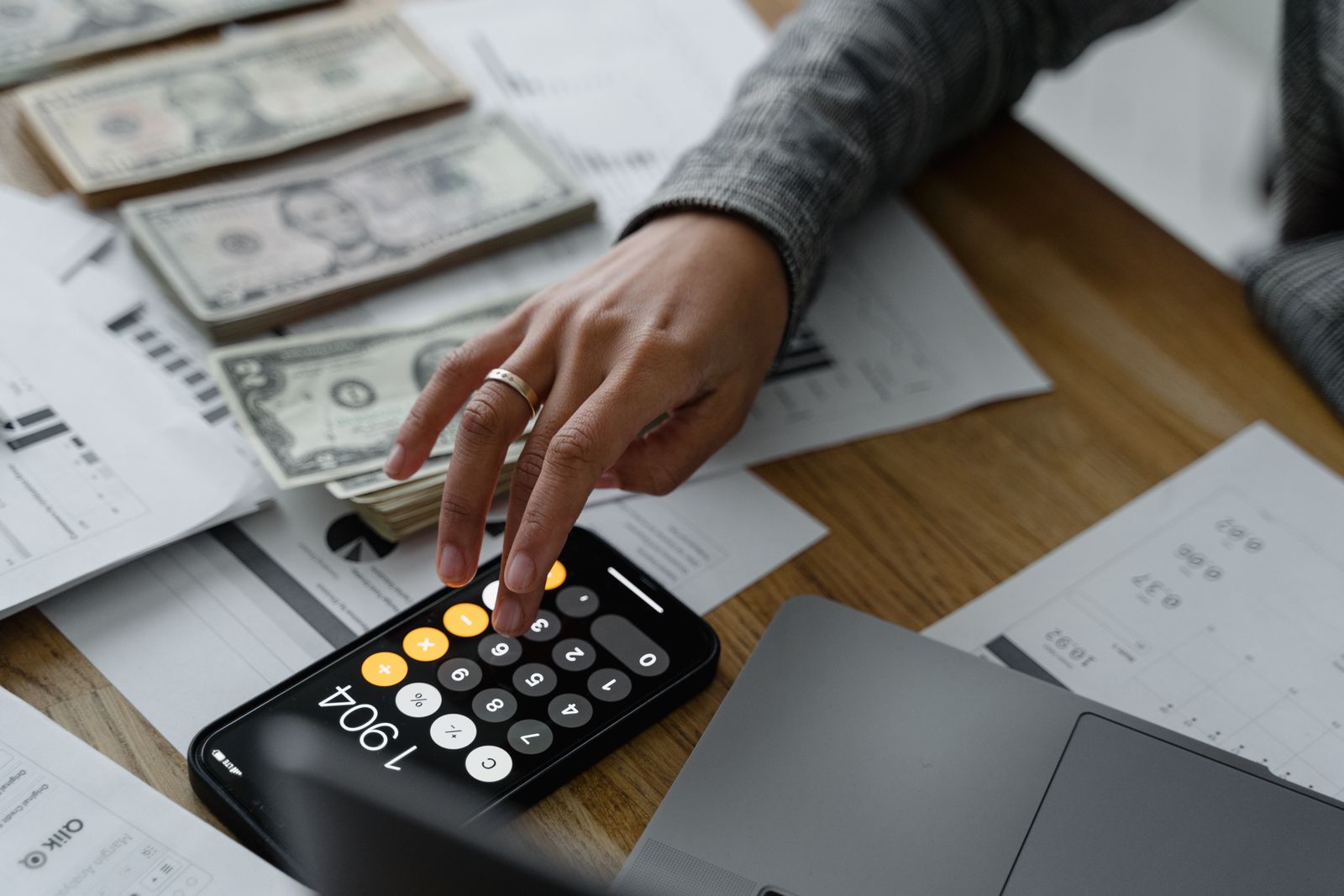 Person using a smartphone calculator next to cash and financial documents