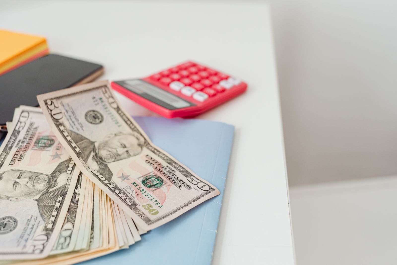 Notebooks, US dollars and a red calculator on a desk